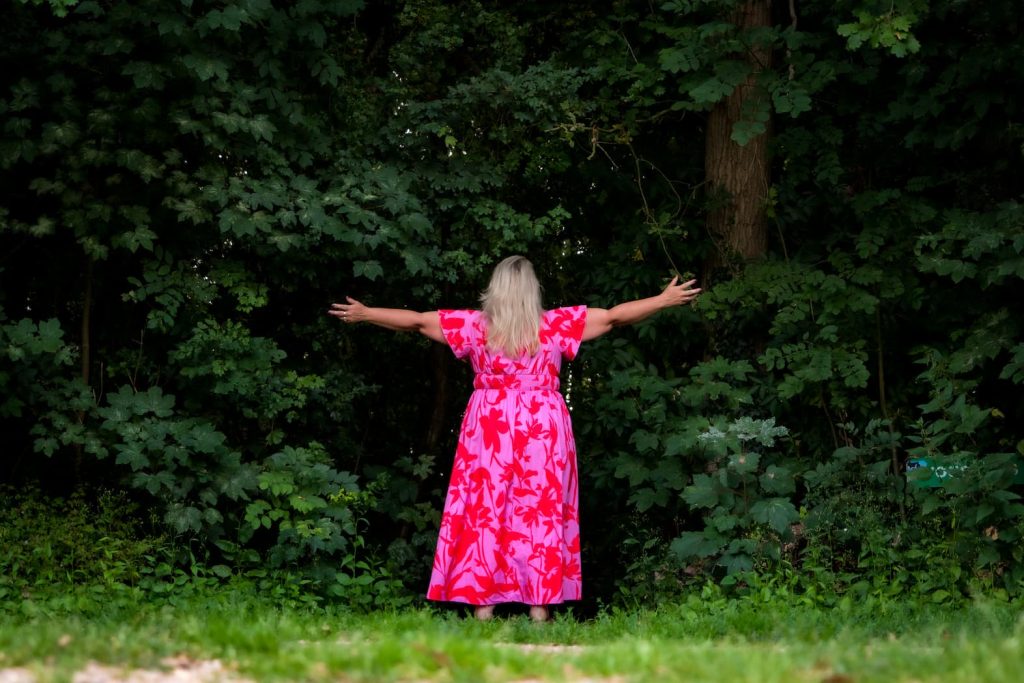Van pleaser naar powervrouw - Claudia Thoen, Holistisch therapeut in Naaldwijk met armen gespreid in het bos